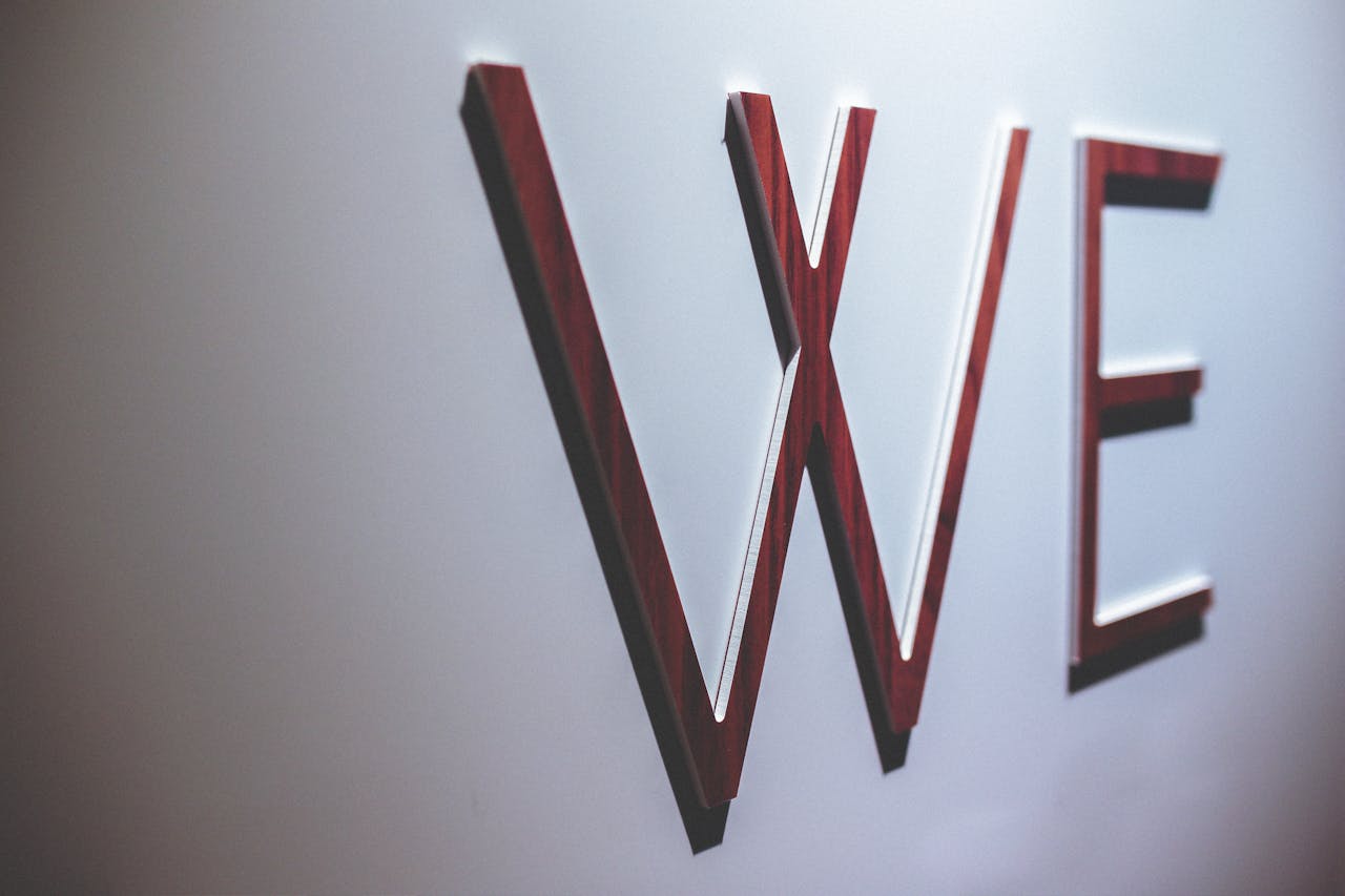 Abstract image depicting wooden letters spelling 'WE' on a white wall.